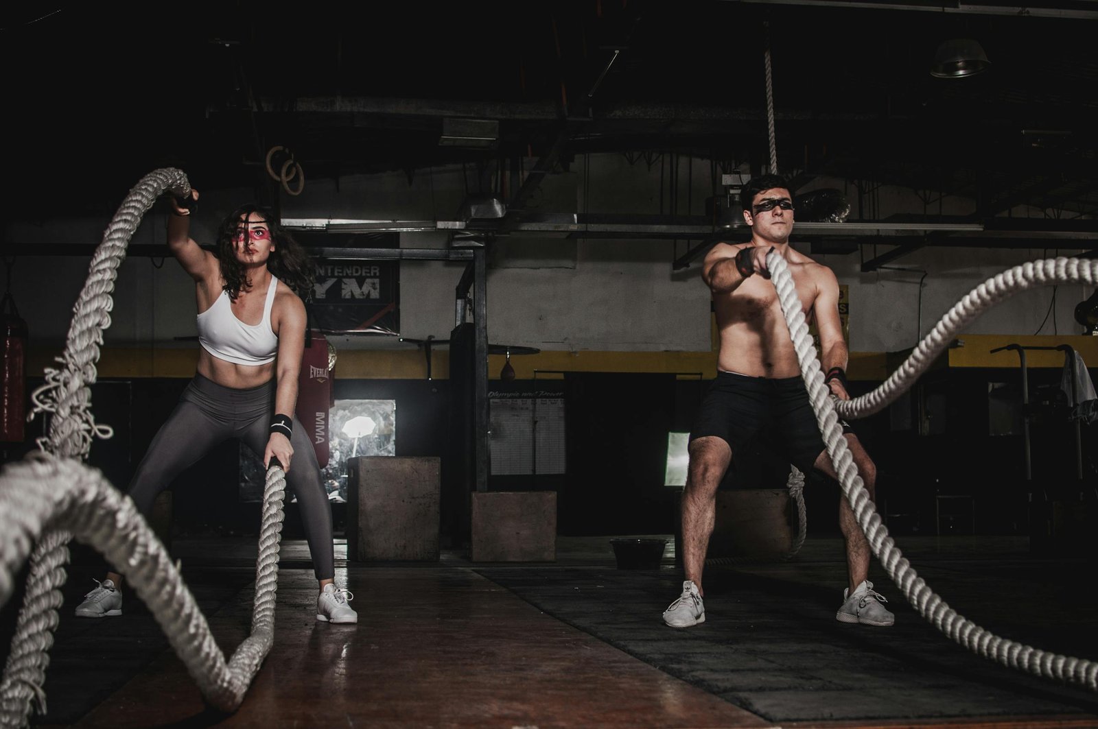 ServiceResistanceTraining Two people engage in a powerful indoor battle rope workout, showcasing strength and energy.