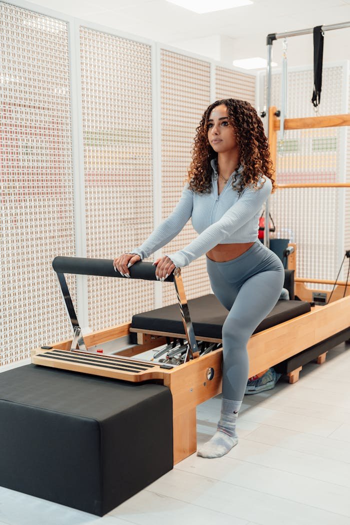 why-choose-us Woman exercising on pilates reformer machine indoors. Focus on fitness and wellbeing.